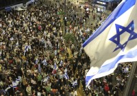 Parenti e sostenitori degli ostaggi israeliani detenuti a Gaza da parte dei militanti di Hamas tengono cartelli e sventolano bandiere israeliane durante una manifestazione davanti al Ministero della Difesa a Tel Aviv