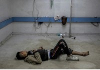 Un giovane palestinese ferito da un bombardamento israeliano giace a terra in attesa di cure mediche all&#039;ospedale Al-Shifa di Gaza City