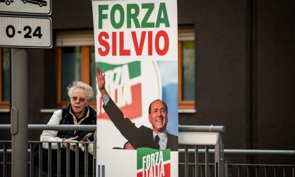 Una simpatizzante del leader di Forza Italia dietro al totem di Berlusconi all&#039;ingresso del San Raffaele di Milano  