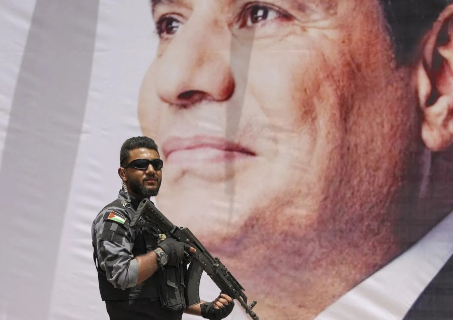Un membro delle forze di sicurezza di Hamas di fronte a un ritratto di Al Sisi