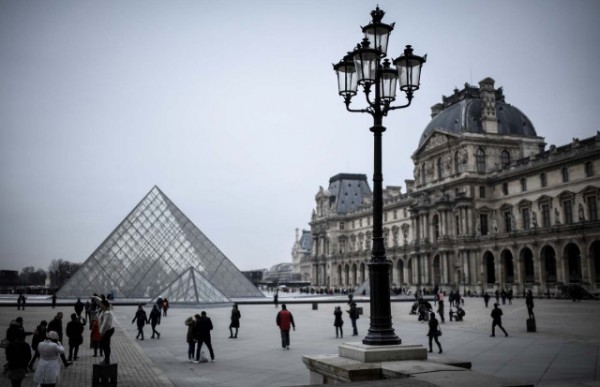La gente camina hacia la Pirámide del Louvre en París