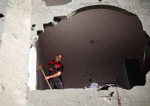 Macchie di sangue visibili sul muro mentre un uomo spazza le macerie di un edificio colpito dai bombardamenti israeliani a Rafah, nel sud della Striscia di Gaza, il 3 maggio 2024