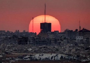 Questa foto, scattata da una posizione al confine israeliano con la Striscia di Gaza, mostra il sole che tramonta dietro gli edifici distrutti nei territori palestinesi